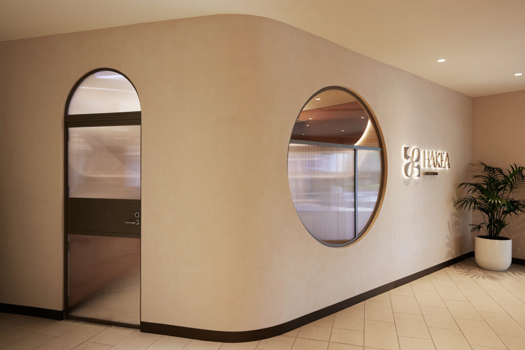 Modern bright interior, wellness centre entry, circle window, arched glass door, bronze frames, fluted glass, limewash walls