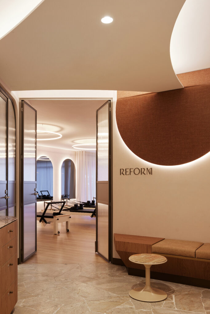 Modern interior, reform pilates, fabric panel, fluted glass, bronze, timber, leather seating, marble, earthy tones, limewash