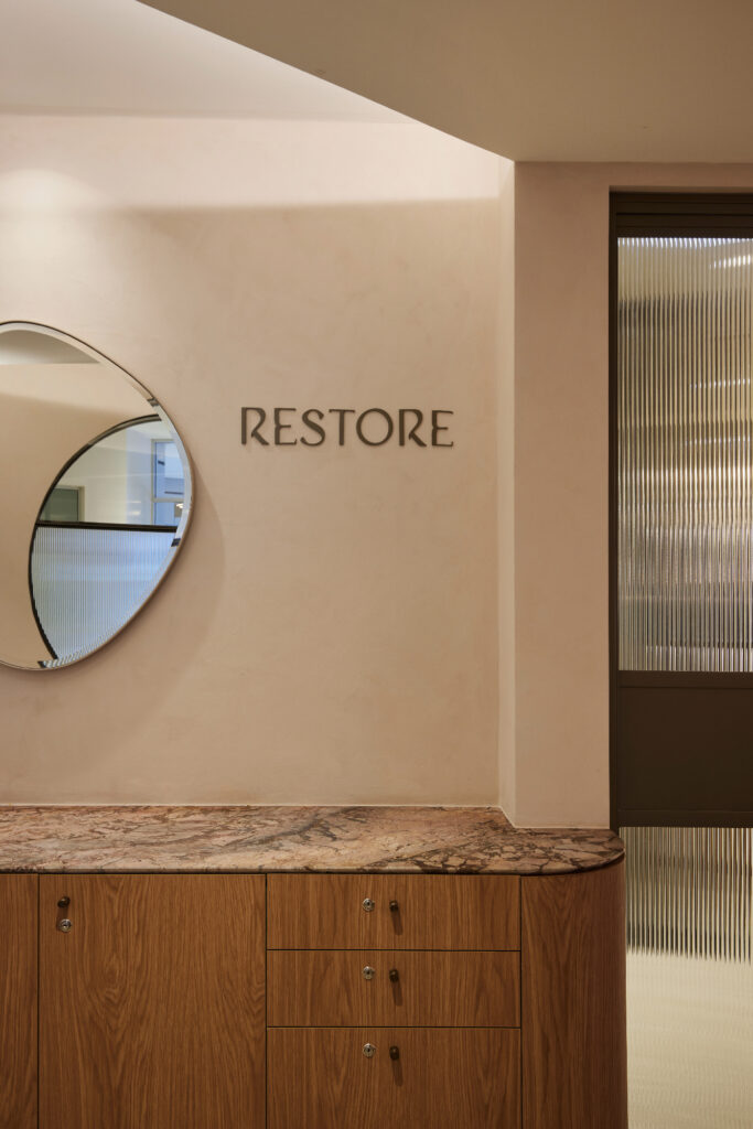 Modern wellness centre interior waiting room fluted glass, bronze, timber veneer credenza, marble, earthy tones, limewash